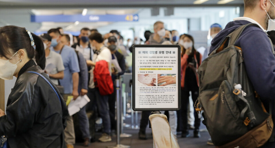 인천국제공항 제1터미널 입국장에 해외입국자들이 검역을 받기 위해 대기하고 있다. 승객들 앞에는 원숭이두창 관련 안내문이 세워져 있다. (사진=연합뉴스)