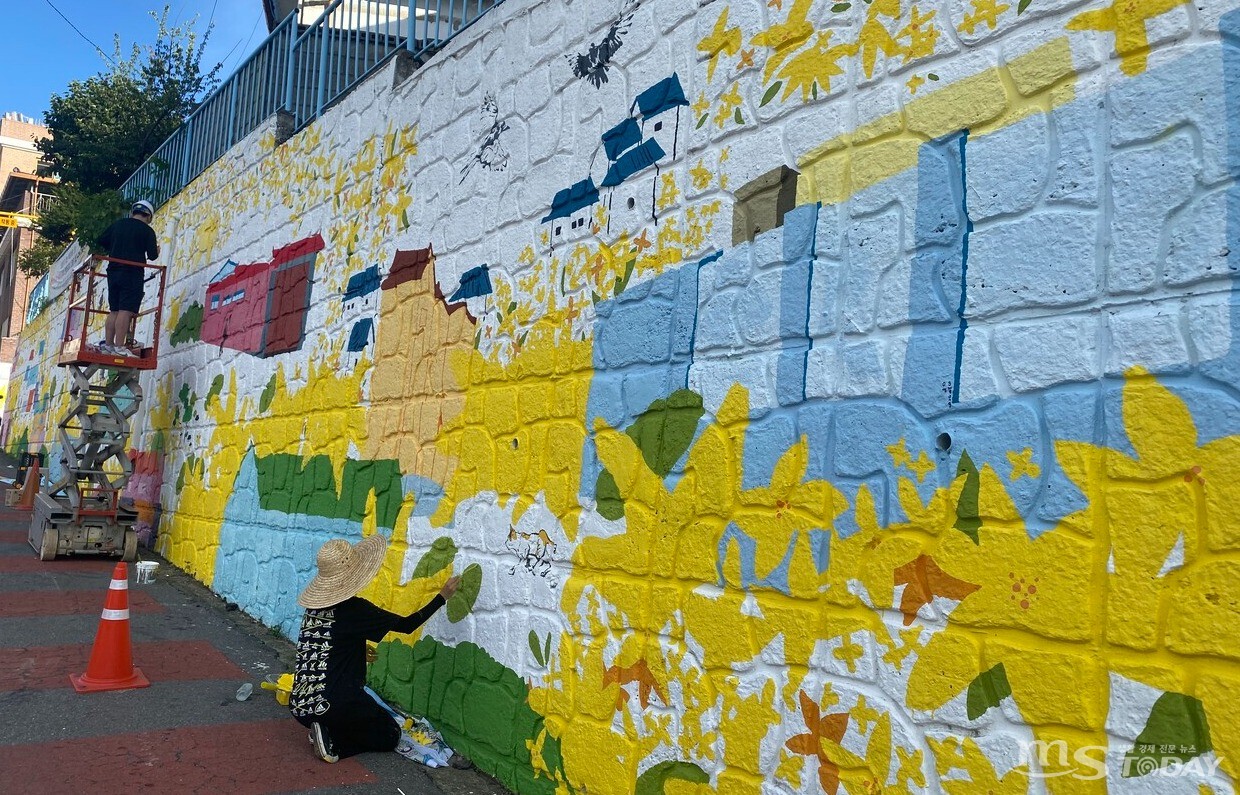 나누스페이스와 지역 청년작가들이 효자동 낭만골목에서 개나리에서 영감을 얻은 벽화를 그리고 있다. (사진=나누스페이스)
